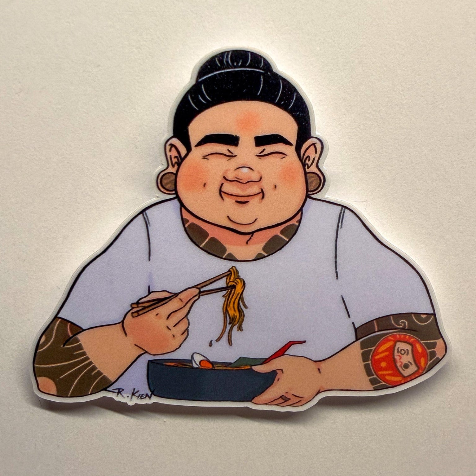 Sticker of a cartoon character eating ramen noodles with chopsticks on a plain background